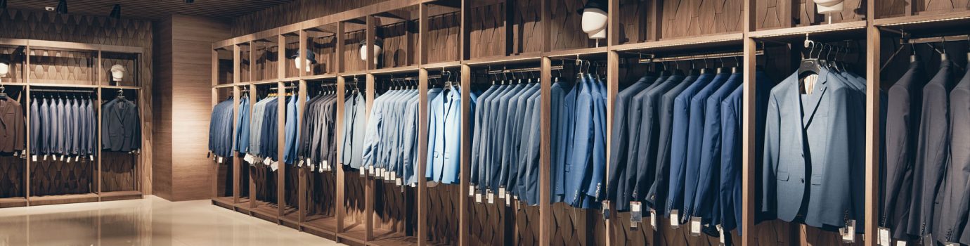 Strict premium suits Interior of the business suit shop. Strict premium expensive suits hang in a row on hangers in large quantities